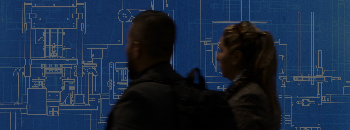 A man and woman are positioned in front of a detailed blueprint, discussing plans in a professional setting