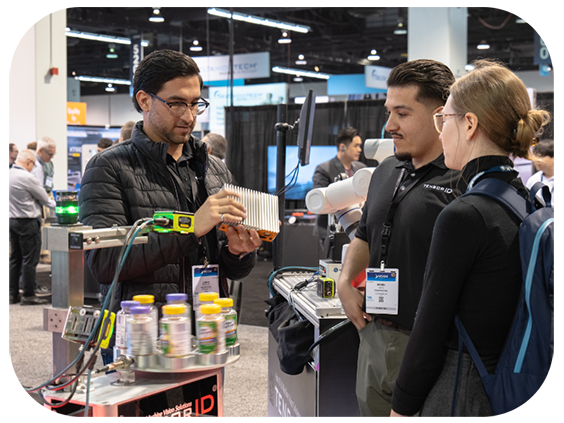  woman and two men gather around a machine, discussing its features in a technical environment