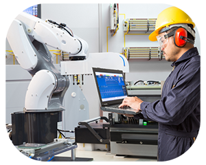  A man wearing a hard hat and safety glasses is focused on working on a laptop