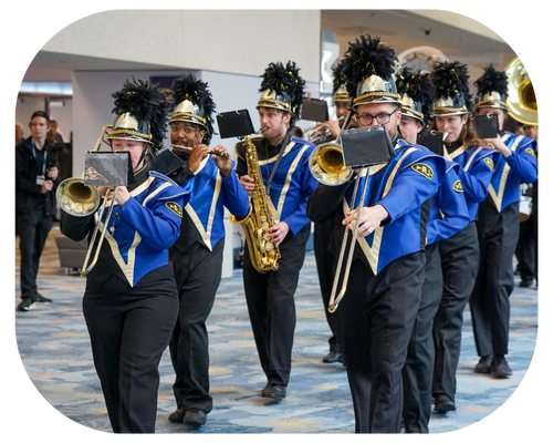 A diverse group of musicians in blue and gold marching band uniforms gathers, preparing for their upcoming performance