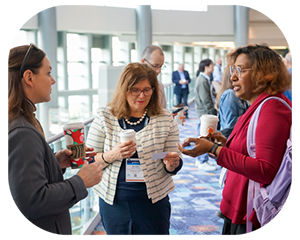 Three women engaged in conversation at a conference, sharing ideas and insights in a professional setting