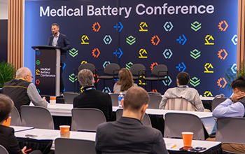 Speaker presenting in front of medical battery conference stage