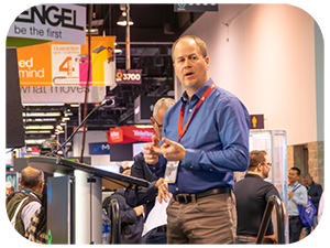 A man delivers a speech from a podium to an attentive audience in MD&M West