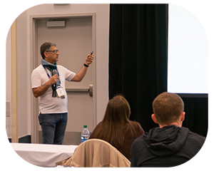 A man presenting to an audience, engaging with the group while using visual aids to enhance his messagephoto