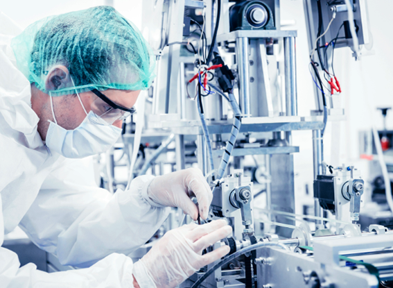  A man in a white lab coat operates a complex machine in a laboratory setting, focused on his task.