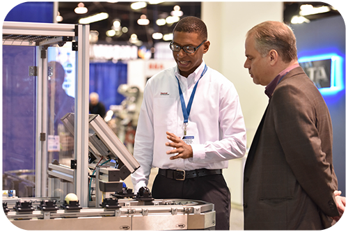 Two men are positioned in front of a machine, engaged in conversation about its functionality and use