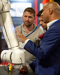 Two men in suits observe a robot, engaged in discussion about its features and capabilities