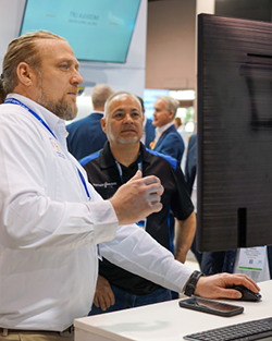 A man wearing a white shirt is attentively looking at a computer screen, engaged in his task
