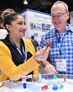 A man and woman examine a display featuring various colored plastic parts in a well-lit environment