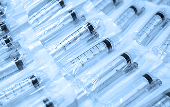 Medical syringes in a package. A bunch of unused, packaged syringes.Many new syringes lie strewn on a flat surface