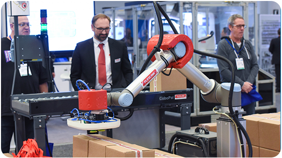 A diverse group of people gathered around a humanoid robot, engaging in conversation and observation