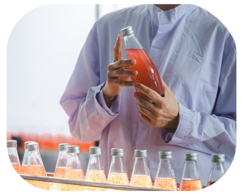 A man wearing a lab coat displays bottles of liquid, surrounded by laboratory equipment and shelves